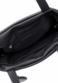 Intérieur d'un sac à main en cuir noir présentant une finition texturée, avec une poche zippée et un revêtement en tissu. Poignées lisses et étiquette de marque discrète incluse.