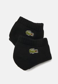 Chaussettes en coton noires avec des poignets côtelés et un logo de crocodile vert brodé. Texture douce avec un ajustement serré et un design de orteil arrondi.