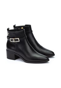 Botas de cuero negro hasta el tobillo con punteras afiladas, tacones anchos y una correa decorativa con hebilla. Textura suave y un detalle minimalista.