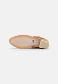 Beige Wildleder-Schuh mit strukturierter Oberfläche, ausgestattet mit einer glatten, hellen Gummisohle und detaillierten Nähten an den Kanten.