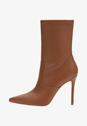 Bottine en cuir marron avec un bout pointu, une forme effilée, des détails de coutures et un talon haut stilettos. Texture lisse et style minimaliste.