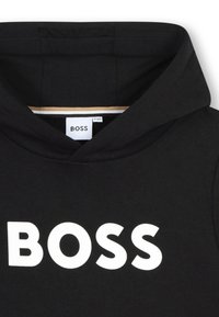 Melna kapuce ar lielu balto "BOSS" logo. Ar auklu regulējamu kapuci un mīkstu kokvilnas audumu ar gludu tekstūru.