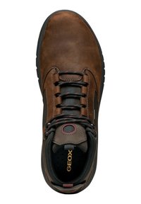 Zapato de cuero marrón con suela de goma negra, que presenta un upper texturizado, puntera redondeada y cordones en contraste rojo y gris. Detalle del logo dorado visible.