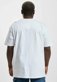 Tricou alb din bumbac, cu mâneci scurte, croială lejeră și spate simplu. Textură moale, design clasic cu gât rotund, potrivit pentru îmbrăcăminte casual.