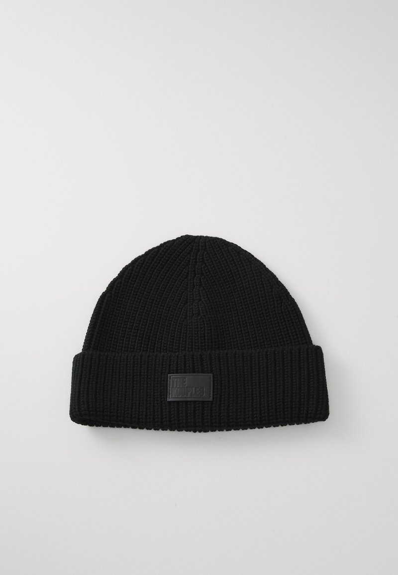 Black knitted beanie with folded brim and rectangular patch detail on a plain white background.