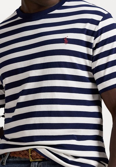 Tumši zilas un baltas svītrainas kokvilnas T-krekls ar apaļu kakla izgriezumu un īsām piedurknēm, ar mazu sarkanu polo logo uz krūtīm.