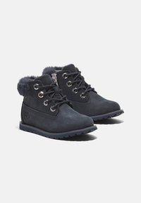 Botines oscuros de cuero suave con un cuello de piel sintética, puntera redonda, ojales de metal y una suela de goma con relieve.