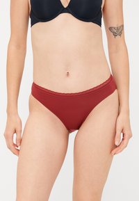 Bikini rosso di cotone con rifinitura in pizzo sulla vita. Presenta un taglio moderato e materiale elastico per il comfort.