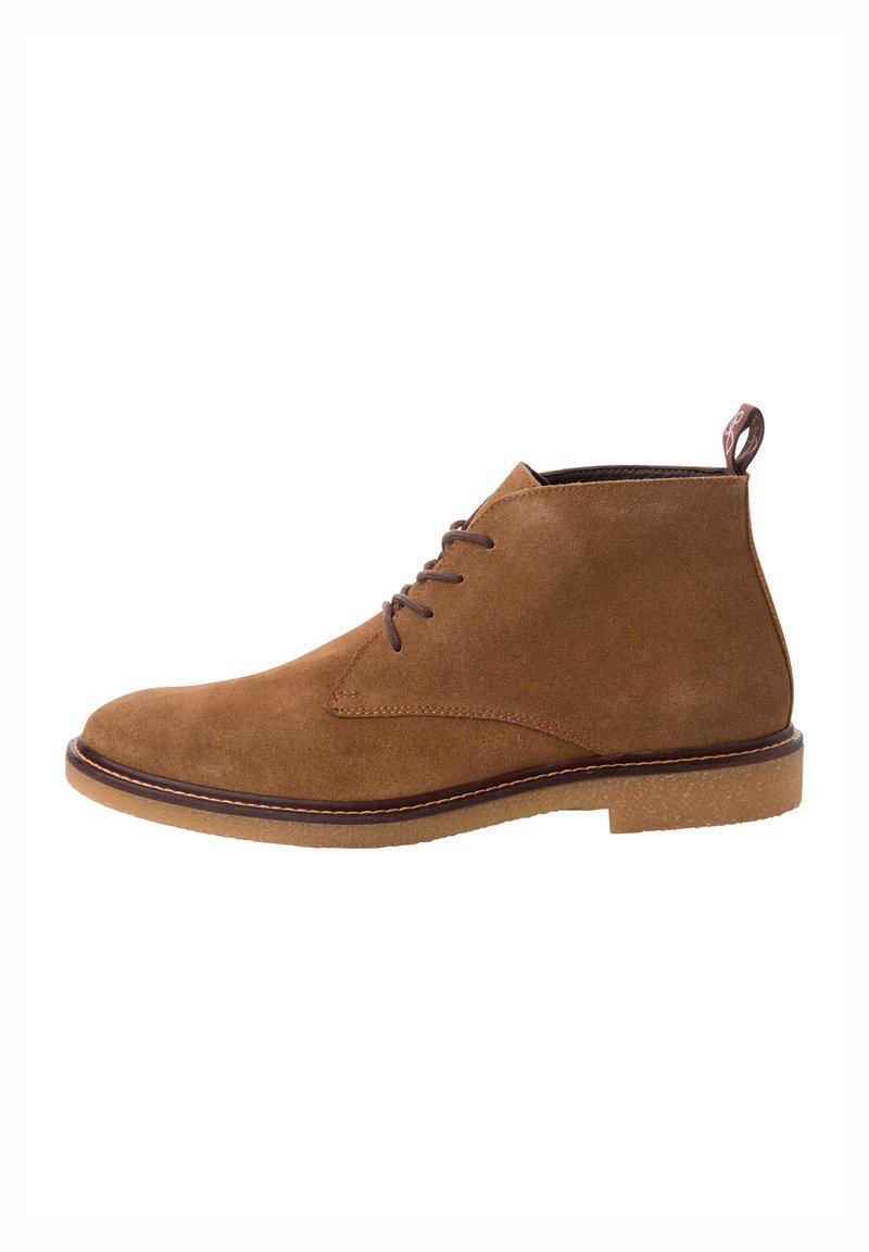 Bottine en daim marron avec bout rond, design à lacets, accents en cuir et semelle en caoutchouc texturé. Comprend une languette à l'arrière.