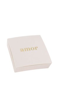 Caja cuadrada de color crema con una textura suave; presenta "amor" en tipografía dorada en la tapa; diseño minimalista sin patrones.
