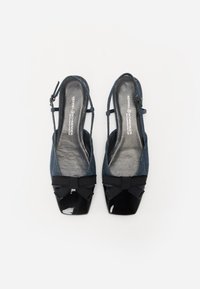 Chaussures slingback en denim avec un bout en noir brillant, ornées d'un ruban noir noué à l'avant. Tige texturée avec une forme structurée.
