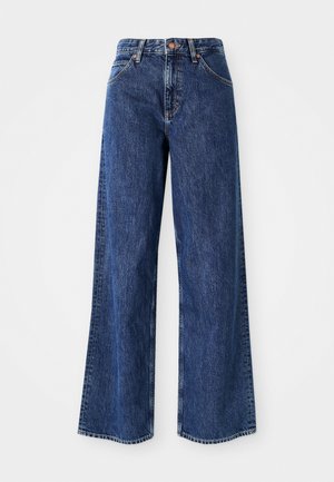 Jean en denim bleu à jambes larges avec taille haute, coutures visibles, poches avant et texture légèrement délavée.
