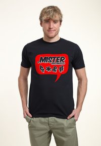 Černé bavlněné tričko s velkým červeným grafickým bublinkovým dialogem, na kterém je text "MISTER ZEKE @ SINCE 1976" a různé symboly. Krátké rukávy.
