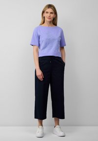 Lavender T-shirt met korte mouwen en een bladontwerp, gecombineerd met marineblauwe wijde broek en witte sneakers. Minimalistische stijl en zachte stoffen.