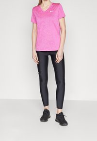 Rosa melange v-ringad t-shirt som matchas med svarta leggings. T-shirten har korta ärmar, medan leggingsen har en slät och elastisk textur.