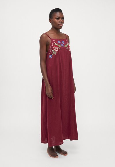 Abito maxi color bordeaux con ricami che presentano motivi floreali in rosa e blu. Tessuto liscio e fluido, spalline sottili, dettaglio con apertura laterale.