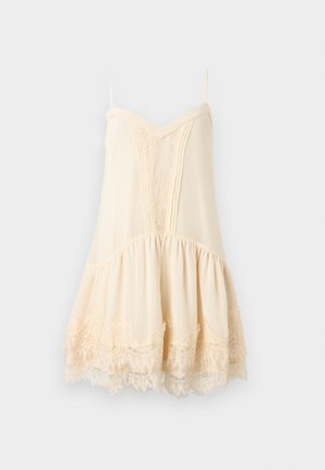 Κρεμ αμάνικο φόρεμα με λεπτές τιράντες, δαντελένιες λεπτομέρειες στο μπροστινό μέρος και το τελείωμα, και φούστα με βολάν και μαζεμένο ύφασμα.