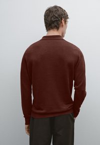 Maglione a maglia color marsala con colletto polo classico, maniche lunghe e orlo a coste, visto da dietro con una texture liscia.