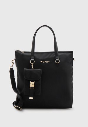Czarna torba typu tote z podwójnymi uchwytami, odpinanym paskiem na ramię, małą przednią kieszenią z klamrą oraz złotym logo "Tommy Hilfiger" z przodu.