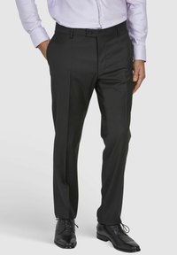 Schwarze Anzughosen aus glattem Stoff, mit geradem Bein-Design, Seitentaschen, Gürtelschlaufen und einem Knopfverschluss. Kombiniert mit schwarzen Schuhen.