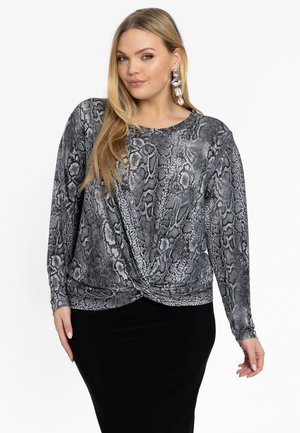 Langarmtop in grijs en zwart slangenprintstof met een geknoopt detail op de taille, gecombineerd met een zwarte aansluitende rok.