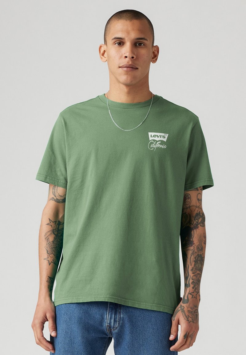 Groene katoenen t-shirt met een ronde hals, korte mouwen en witte grafische tekst op de linkerborst. Soepele textuur, relaxed fit.
