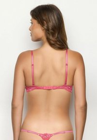 Soutien-gorge en dentelle rose avec des bretelles fines et ajustables, une fermeture à crochets et œillets, et une texture douce et délicate. La vue arrière met en valeur le design en dentelle complexe.