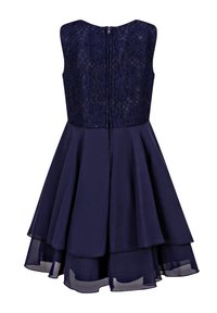 Marinblå klänning med spetsliv, ärmlös design och lager på lager kjol med en genomskinlig nederkant, stängs med en dragkedja bak.