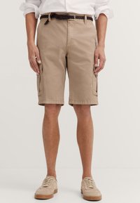 Beige cotton cargo shorts with two side pockets, a woven brown belt, and a relaxed fit, ending just above the knee. Textured fabric.