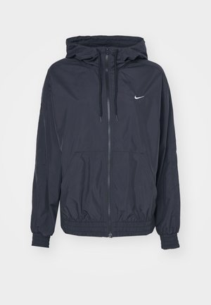 Jachetă Nike neagră, tip windbreaker, cu fermoar în față, glugă cu șnur, manșete elastice și buzunare laterale, având un logo subtil pe piept.