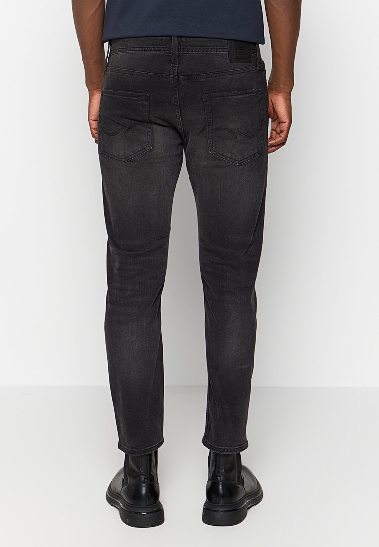 Schwarze Slim-Fit-Jeans mit einer glatten Denim-Textur. Verfügt über zwei Gesäßtaschen mit dezenten Nähten und einem mittelhohen Bund.