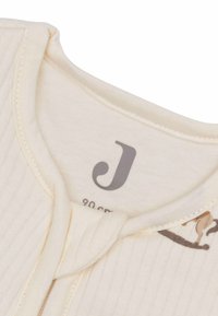 Body en rib ribé couleur crème avec un col rond et une fermeture à pression à l'avant ; présente un motif de chat imprimé subtil. Taille étiquetée 90 cm.