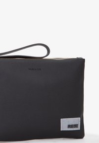 Sort lynlås clutchtaske lavet af tekstureret stof, med et håndtag og en lille hvid label med farverige prikker og teksten "RENEW VITA."