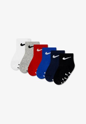 Seks par Nike babysokker i hvid, grå, rød, blå, marineblå og sort, hver med Nike swoosh-logoet nær manchet og sål.