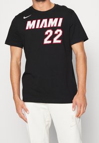 Czarny bawełniany T-shirt z napisem "MIAMI" w odważnym białym i czerwonym kolorze oraz numerem "22" w białym, obrysowanym na czerwono. Krótkie rękawy i okrągły dekolt.