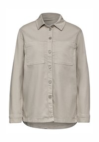 Beige långärmad skjorta med spetsig krage, två bröstfickor och knappar framtill. Tillverkad av mjukt tyg med en slät yta.
