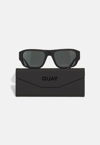 Gafas de sol negras con lentes oscuros, que presentan un diseño de marco cuadrado audaz. Acompañadas de un estuche negro elegante con la inscripción "QUAY" en relieve.
