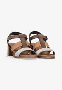 Sandalias de tacón en marrón y blanco que presentan una combinación de materiales lisos y texturizados, diseño de punta abierta y correa ajustable en el tobillo.