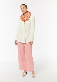 White textured blazer, pink wide-leg trousers, and a colorful checkered scarf in orange, pink, and cream. White heeled sandals complete the look.
