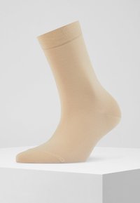 Beżowa skarpetka sięgająca do kostki, wykonana z gładkiego, elastycznego materiału, z rypsowym mankietem. Projekt ma dopasowane wykończenie bezszwowe w okolicy palców dla większego komfortu.