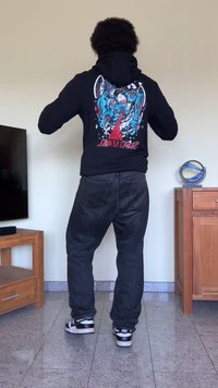 Moletom preto com um design gráfico que apresenta padrões azuis e vermelhos nas costas. Usado com jeans pretos largos e ténis Nike pretos.