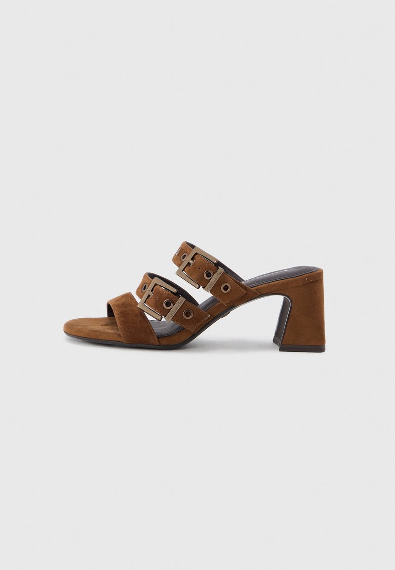 Καφέ σουέντ σανδάλια με τακούνι, διαθέτουν δύο φαρδιές λωρίδες με μεταλλικές αγκράφες, ανοιχτή μύτη και σχεδιασμό με τετράγωνο τακούνι.