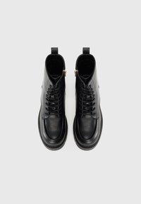 Black leather ankle boots with a smooth finish, lace-up front, side zippers, and a textured sole, featuring rounded toes and tab accents.