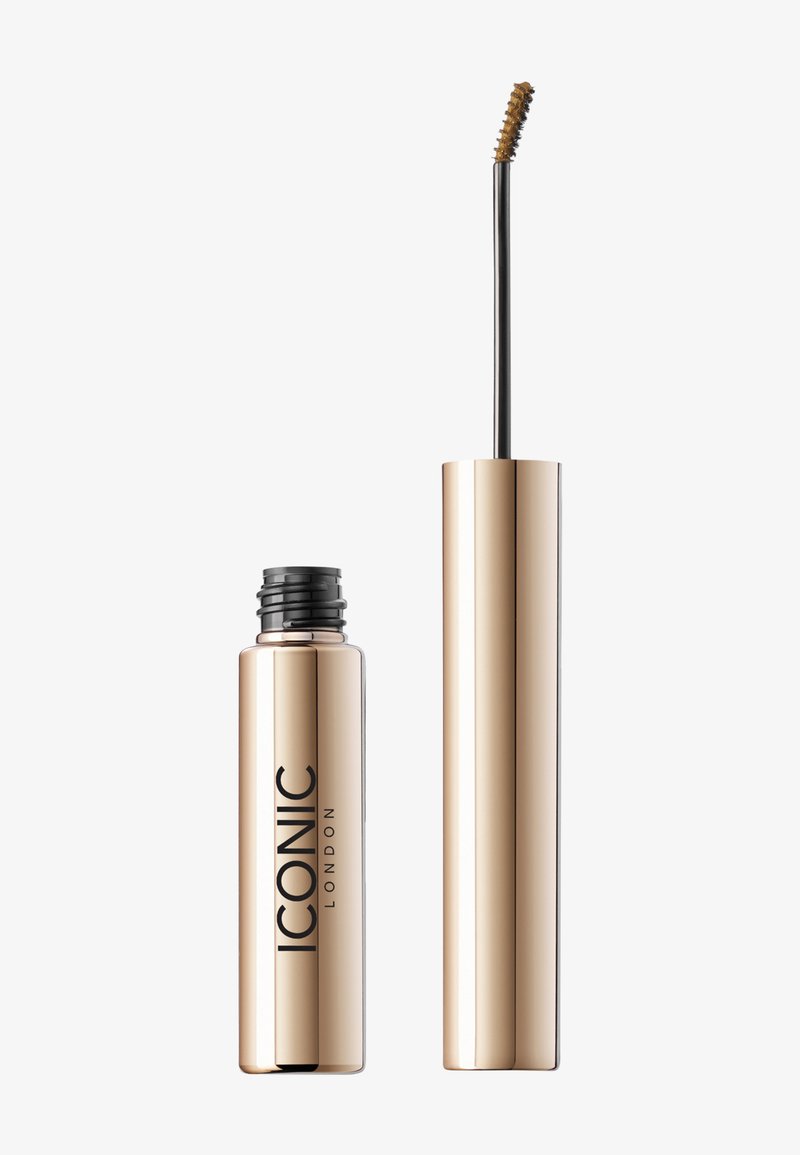 Tube de mascara métallique doré avec un capuchon noir bien visible et un applicateur allongé avec une pointe courbée et des poils courts.