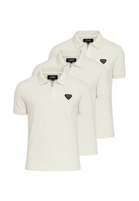 Tre cremede polo shirts lavet af bomuld, med kravehals og lynlås foran. Hver har et sort logo-patch på venstre bryst.