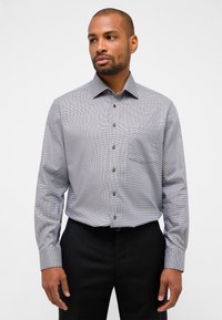 Grau karierte Langarmshirt mit Button-Down-Kragen, einer Brusttasche und dunklen Knöpfen, kombiniert mit schwarzen Hosen.