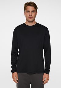 Musta pitkähihaista T-paitaa, jossa on pyöreä kaula-aukko ja slim fit -leikkaus. Valmistettu sileästä, kevyestä kankaasta, jossa on huomaamaton logo rinnassa.