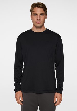 Zwarte lange mouwen T-shirt met een ronde hals en een slim fit. Gemaakt van een gladde, lichte stof, met subtiele branding op de borst.