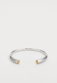 Pulsera de brazalete de metal plateado con acabado suave y pulido, que presenta dos acentos dorados redondeados en los extremos abiertos.