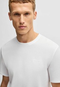 Witte t-shirt met een ronde hals en een subtiel geperst "BOSS"-logo op de linkerborst. Glad materiaal, casual pasvorm.